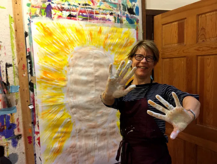 Photo of a woman painting with her hands at a Painting Experience workshop