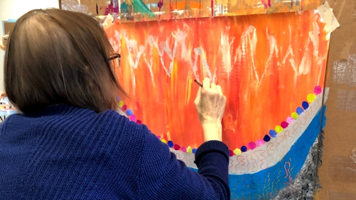 Woman working on brightly colored orange process painting